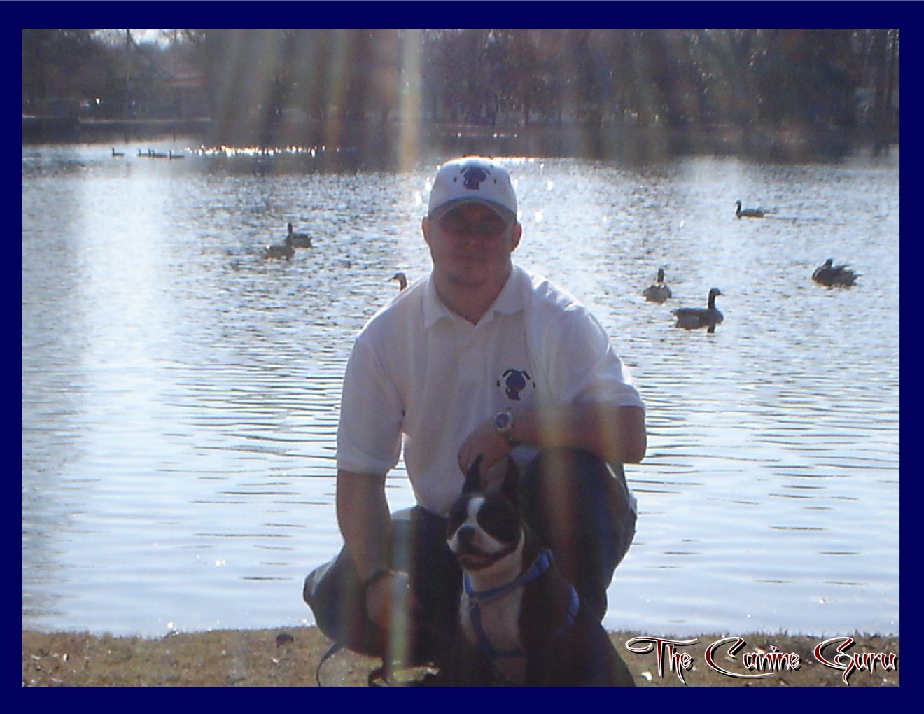 Brandon Ross outdoors with Stoli, a small black-and-white dog in a blue harness.