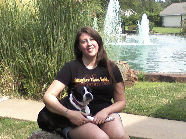 Laura Ross outdoors with a Boston Terrier on her lap.